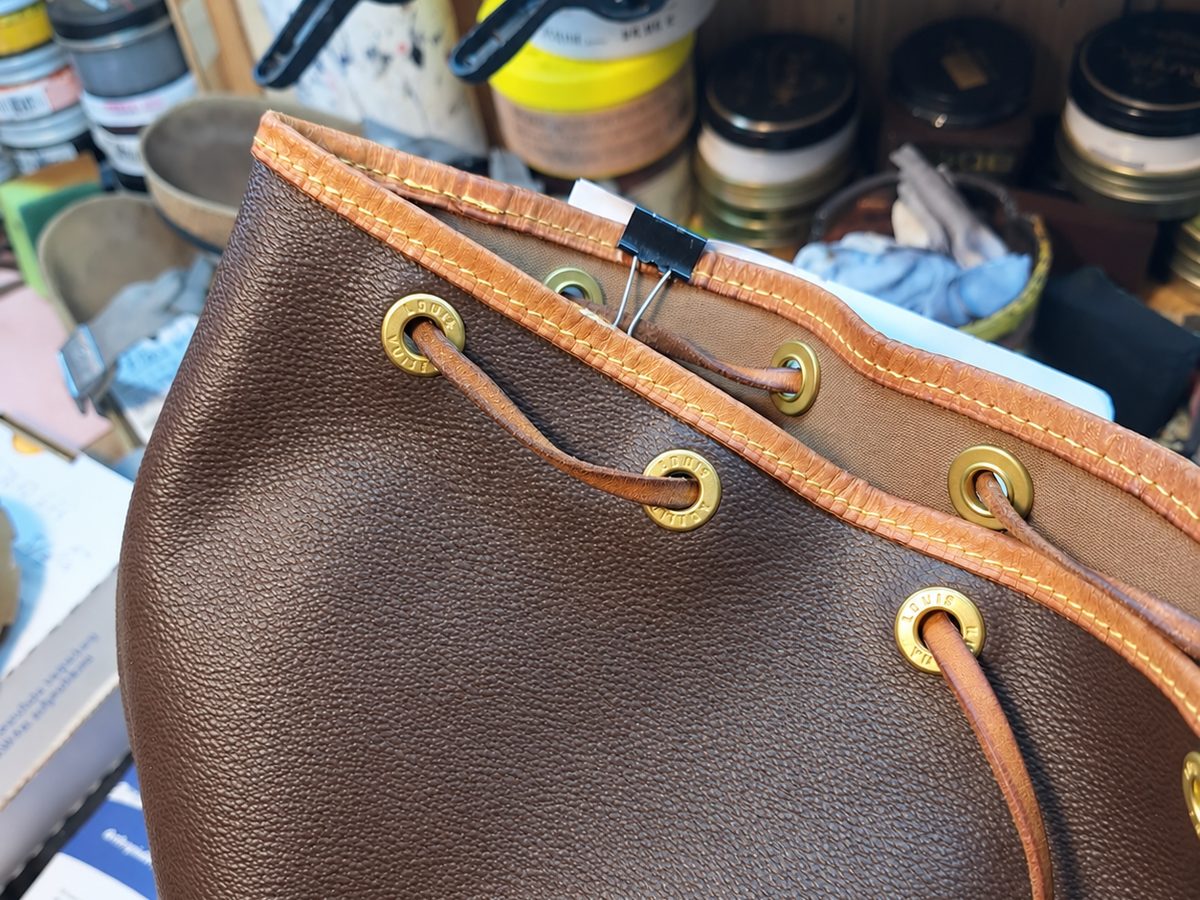 Lederhandtasche in der Werkstatt, die genähte obere Kante mit den Ösen und dem Zugriemen
